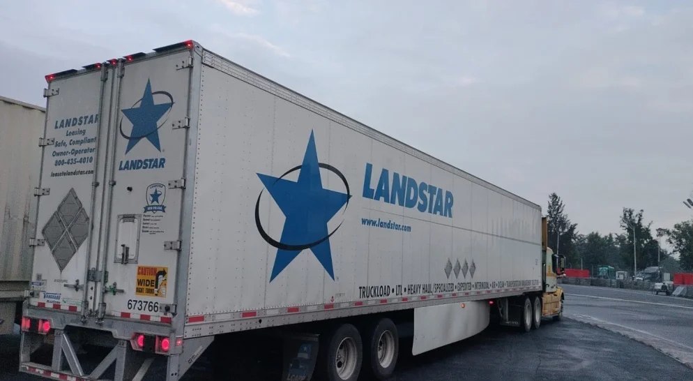 Landstar trailer staged at a Canada cross-border inspection yard at dusk.